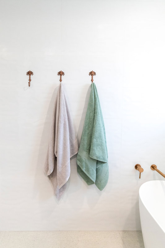 coastal bathroom style in bathroom renovation  by Northern Rivers Bathroom Renovations. Featuring copper palm tree towel hooks on white ripple wall tiles.