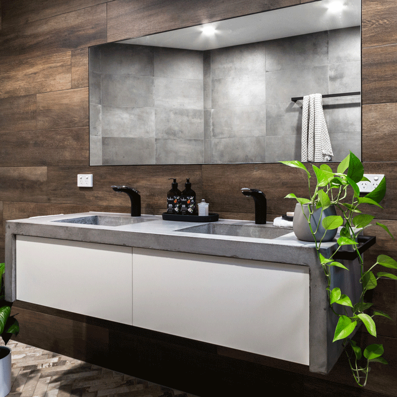 Urbane Industrial style bathroom featuring herringbone floor tiles, timber look walls and custom concrete vanity tops, in Alstonville, NSW By Northern Rivers Bathroom Renovations.