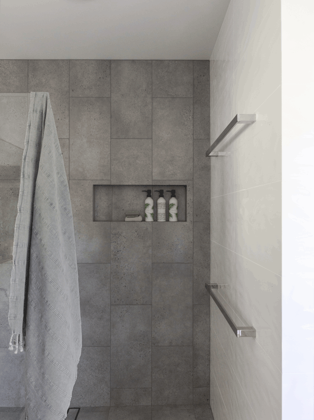 bathroom renovation in Lismore By NorthernRivers Bathroom Renovations featuring concrete look floor tile extending up shower wall. Walk in shower and freestanding bathtub.