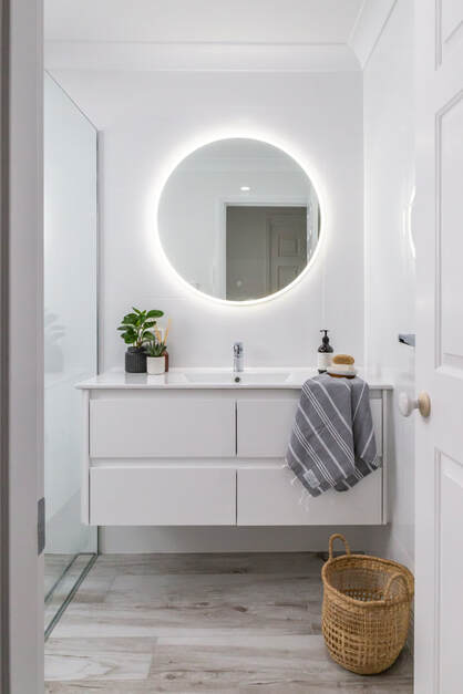 White wall hing vanity with round LED mirror in bathroom renovation in Ballina NSW by Northern Rivers Bathroom Renovations.