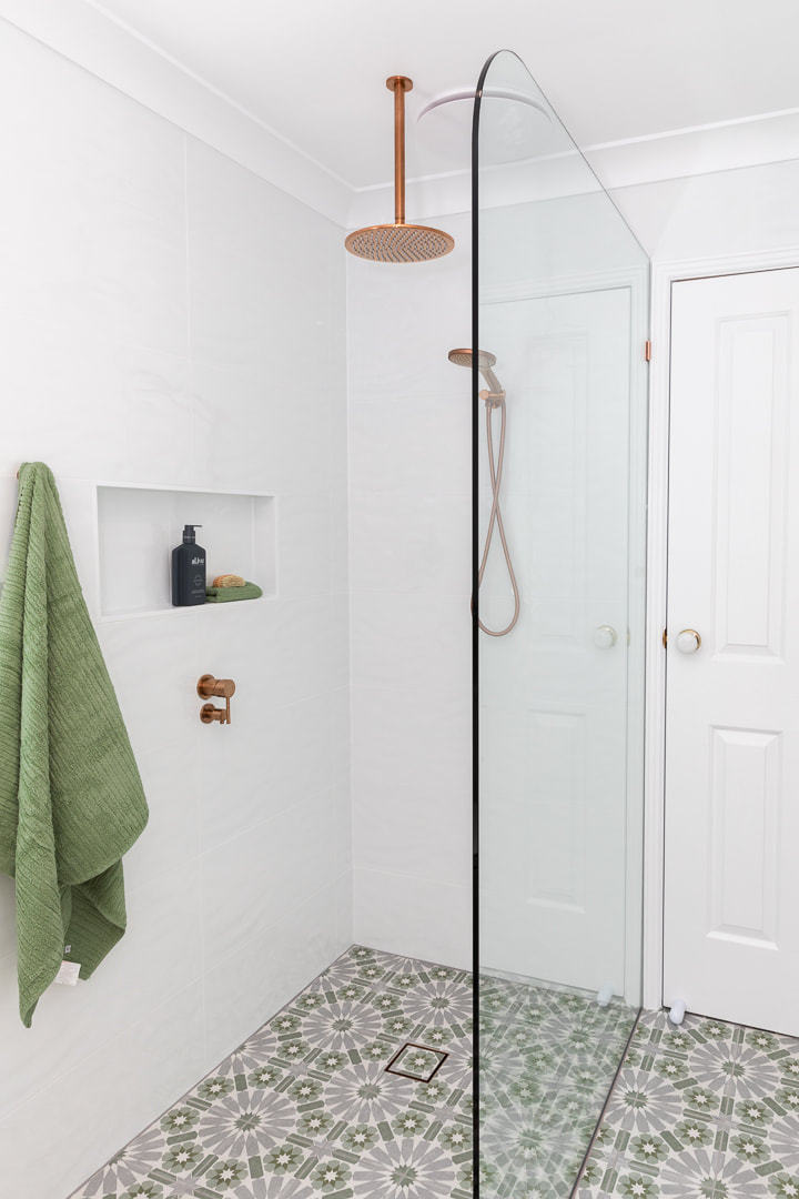 walk in shower with radius shower screen, copper tapware, bold grey and green antico rush encaustic floor tiles.